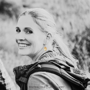 Model wearing Raven Sunrise Oval Earrings, displaying how they hang from the ea