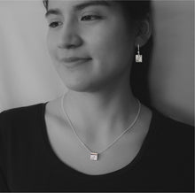 Sterling silver square earrings and necklace with Canadian symbols on black and white model photograph.